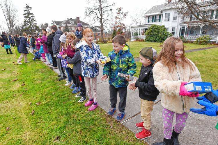 Northfield Elementary School students and staff members pass nonperishable food items from the school to the Northfield Food Pantry at Dickinson Memorial Library on Tuesday.