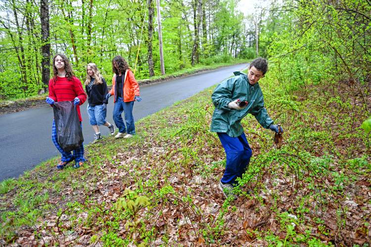 Hendrick Carew, right, and other students from Four Rivers Charter Public School pick up trash along Eunice Williams Drive in Greenfield near the covered bridge on Wednesday.