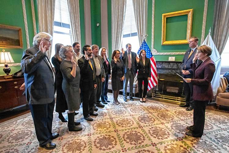 Gov. Maura Healey, standing alongside Housing and Livable Communities Secretary Ed Augustus, swears in members of the Commission on Unlocking Housing Production on Monday, Jan. 29.