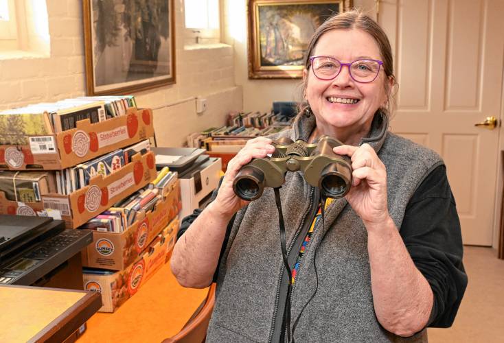 Library Director Laurie Wheeler holds binoculars that are available at Arms Library in Shelburne Falls. The library is working to develop a “Library of Things” this spring.