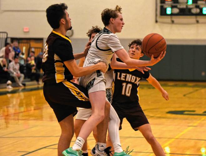 Greenfield’s Grayson Thomas (5) tries to get a shot up while being fouled by Lenox’s Max Shepardson (20) during the Green Wave’s Hampshire League South victory on Friday night at Nichols Gymnasium in Greenfield.